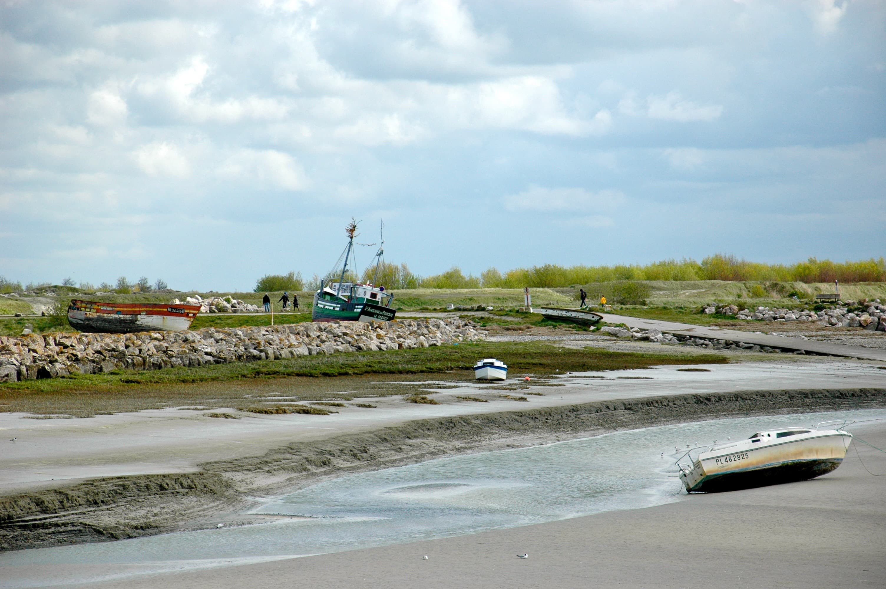 Vue du port du Crotoy au coucher du soleil avec les chalutiers à quai et les façades blanches des villas balnéaires en arrière-plan